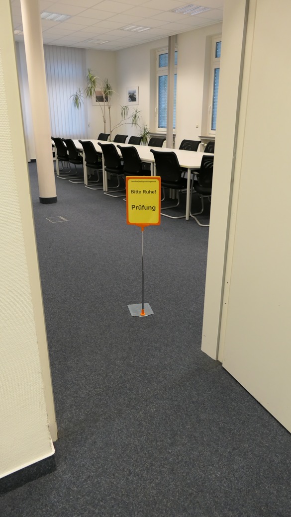 Prüfungssaal. Im Raum steht ein Schild "Bitte Ruhe. Prüfung."
